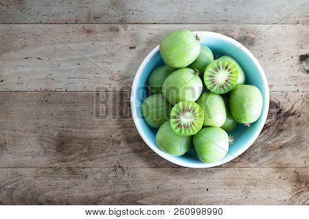 Hardy Kiwi Fruits Or Kiwi Berry Actinidia Arguta In Ceramic Bowl On Wooden Kitchen Table