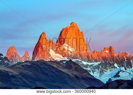 Mountain peak in Patagonia. The grand crimson dawn over the mountain range Fitzroy. Picturesque mountain range, illuminated by the sunrise sun. The concept of extreme, active and photo tourism