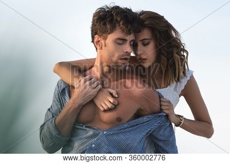Selective Focus Of Passionate Young Woman Touching Boyfriend Torso Against Blue Sky