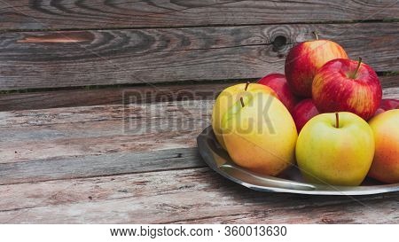 Red And Yellow Apples Lie On A Steel Vintage Plate On Wooden Old Boards Background. Autumn Harvest. 