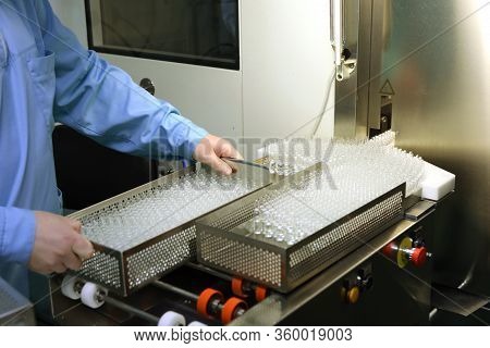 Visual Control Of Ampoules With Medicine. A Woman Works On An Ampoule Production Line. Sterile Bottl