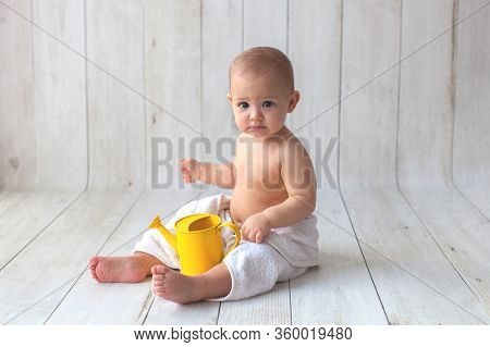 One Yeat Old Baby Girl Is Sitting On Wooden Backgroun In White Towel. After Bath Time.
