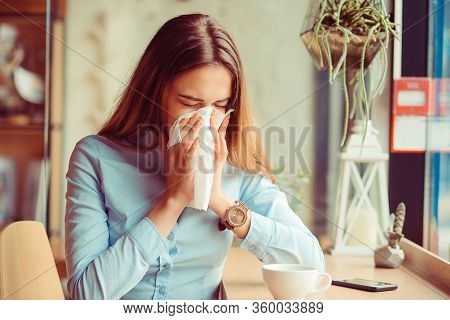 Flu. Young Woman Got Nose Allergy, Flu Sneezing Nose Sitting At The Table In A Trendy Cafe Coffee Sh