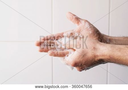 Man Cleaning His Hands Using Liquid Disinfectant Soap And Water In Bathroom.