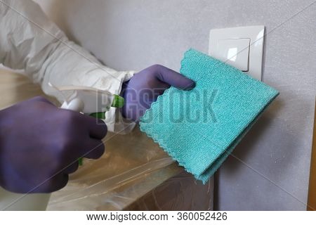 Hand In Glove With Dry Microfiber Cloth Wiping A Light Switch At The Wall From Dust. Early Spring Cl