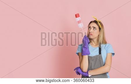 Upset Housewife In Apron And With Rubber Gloves Looks At Brush