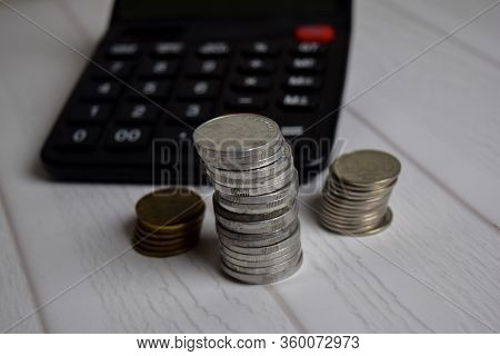 Calculator And The Stack Of Coint Isolated On Office Desk. Calculating Salary Or Tax Concept