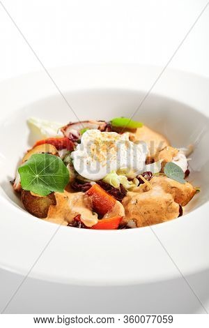 Salad in white bowl. Sliced octopus and fried potato. Served cut ingredients with mayonnaise, tomato spicy ajika and smoked pepper homemade sauce. Restaurant food portion in plate close up