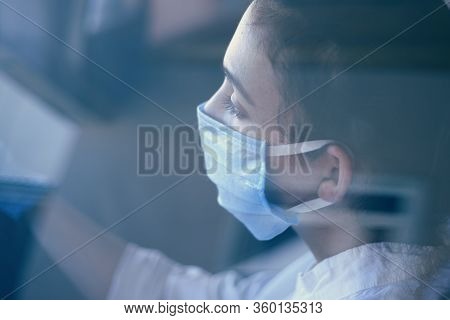 A Young Woman In A Surgical Face Mask And Gloves Driving The Car During Coronavirus Pandemic. A Fema