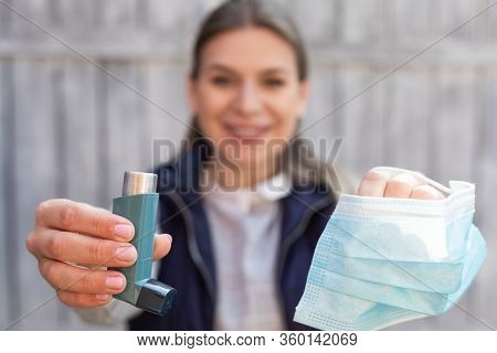 Beautiful Young Woman Holding Asthma Inhaler And Surgical Mask Outdoor