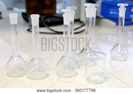 Conducting A Chemical Experiment In A Laboratory. Colored Flasks With Chemical Reagents. Many Glass 