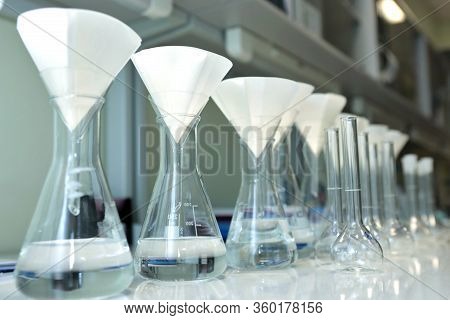 Conducting A Chemical Experiment In A Laboratory. Colored Flasks With Chemical Reagents. Many Glass 