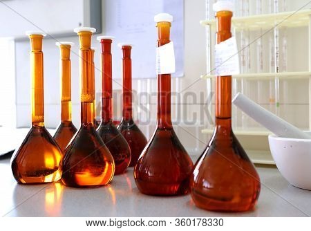 Conducting A Chemical Experiment In A Laboratory. Colored Flasks With Chemical Reagents. Many Glass 