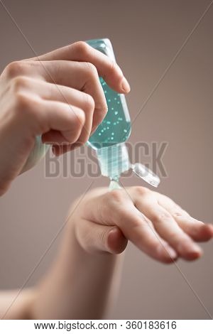 Treatment Of Hands With An Antiseptic Gel. Side View Of Hands With Alcohol Gel On A Beige Background
