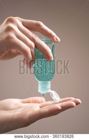 Treatment Of Hands With An Antiseptic Gel. Side View Of Hands With Alcohol Gel On A Beige Background