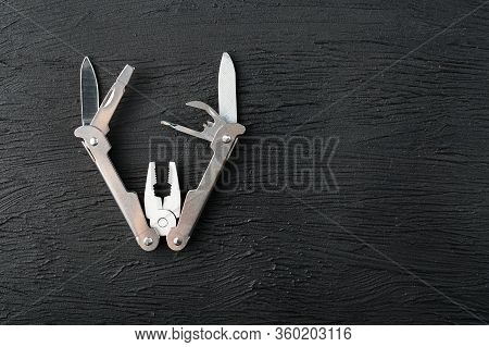 Multi-functional Tool On A Black Textural Background.