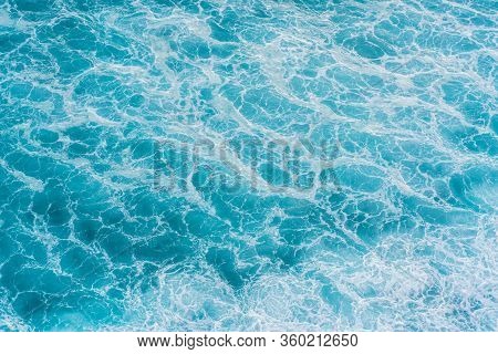The Azure Surface Of The Ocean. Waves Break At The Shore. Texture Of The Water Surface Near The Shor