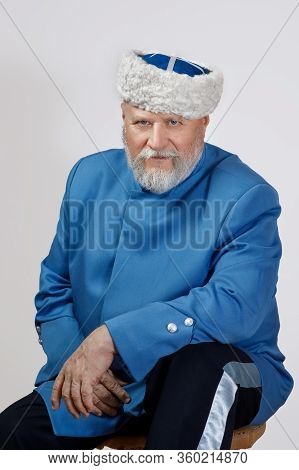 Elderly Man With A Gray Beard In A Hat And A Blue Caftan. Cossack Costume