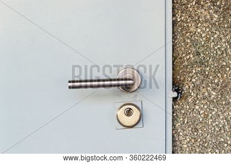Mortise Lock With A Knob And Keyhole On A Metal Door Painted In Gray. Closed Entrance From The Stree