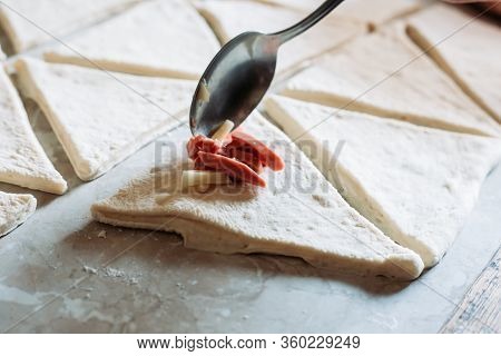 Female Hand Adding Filling With A Spoon To Croissant Roll. Process Of Making Croissant Rolls
