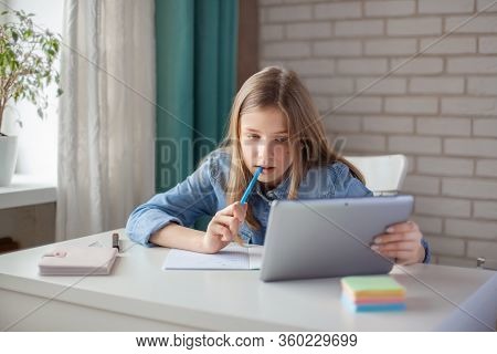 A Cute Girl Does Her Homework Using A Tablet During Self-isolation, While The School Is Closed For Q