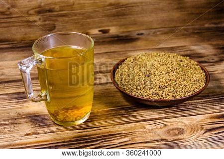 Cup Of Yellow Tea (methi Dana) And Plate With Fenugreek Seeds On Rustic Wooden Table