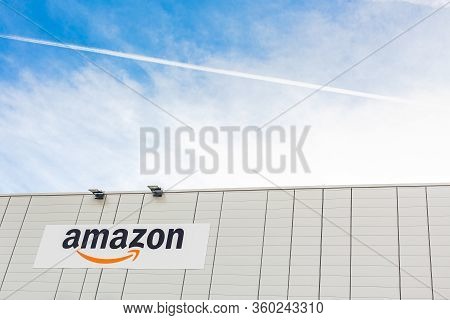 Amazon Logo On The Company Warehouse Building Located In Lyon, France On Bright Blue Sky Background 