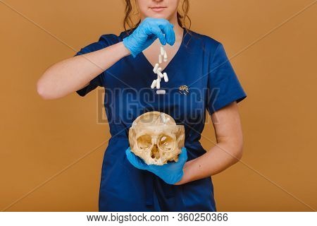 Pretty Young Concentrated Trainee Girl Spills Pills Into A Skull From A Hand Dressed In Disposable G