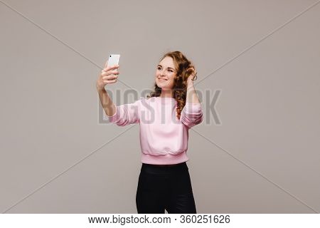 Portrait Of A Young Attractive Woman Making Selfie Photo On Smartphone Isolated On A White Backgroun