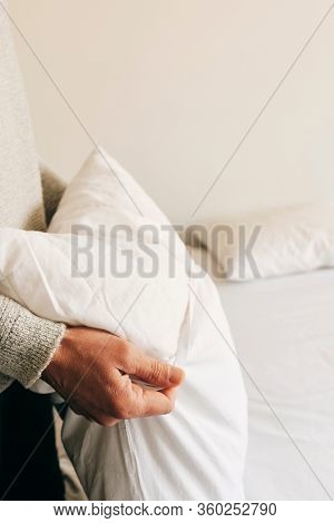 closeup of a young caucasian man introducing a pillow into a white pillow case as he is making the bed
