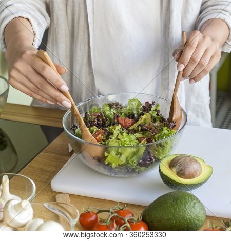 Young Unrecognizable Woman Preparing Vegetable Salad With Avocado In The Kitchen, Close Up Photo