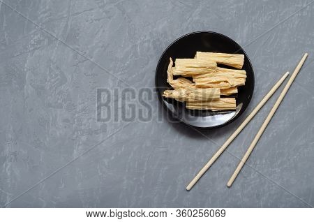 Space For Text. Fermented Soy Tofu Yuba Skin With On A Brown Plate On A Gray Neutral Background With