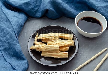 Close Up. Space For Text. Fermented Soy Tofu Yuba Skin With On A Brown Plate On A Gray Neutral Backg