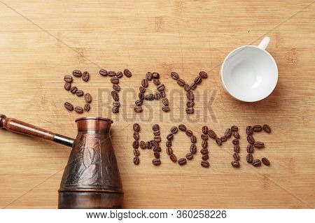 The Slogan Stay Home As Inscription Lined With Roasted Coffee Beans On A Homemade Wooden Cutting Boa
