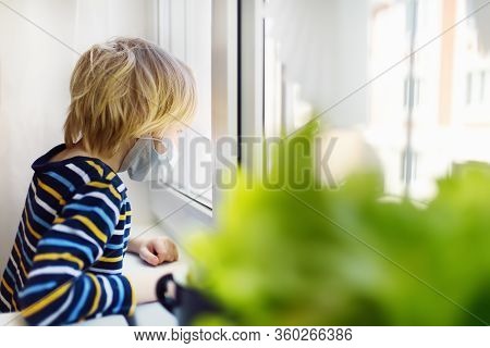 Sed Little Boy Looking Into Window During Coronavirus Pandemic. Child Boring Without Communication A
