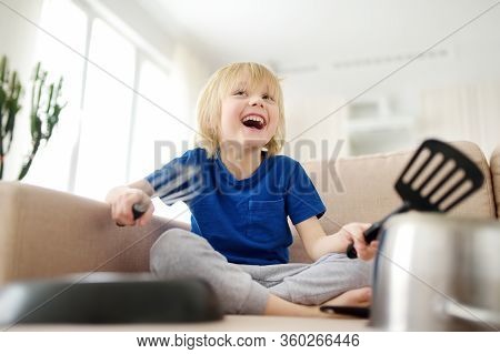 Mischievous Preschooler Boy Play The Music Using Kitchen Tools And Utensils At Home During Quarantin