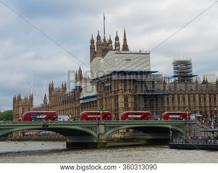 London, United Kingdom- June 2019: Houses Of Parliament And Westminster Bridge With Four Red Double 
