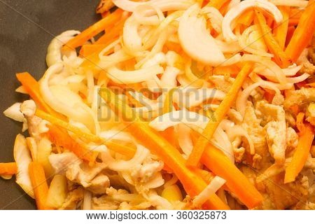 Onions, Carrots And Meat Cut Into Strips Are Fried In A Non-stick Pan. Appetizing Fried Carrots With