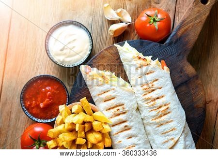 Shawarma, French Fries And Sauces On The Wooden Table. Shawarma Sandwich Is A Most Popular Street Fo