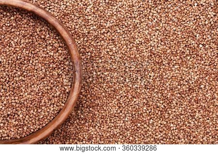 Raw Roasted Buckwheats And Round Wooden Bowl. Russian Grechka. Organic Healthy Diet Food.