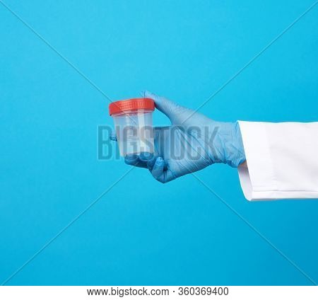 Doctor In A White Coat Holds A Empty Plastic Container For Urine Specimen, Wearing Blue Sterile Medi