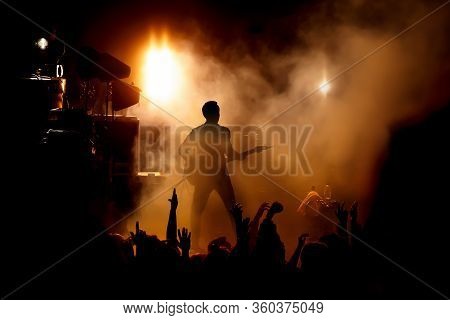 Silhouette Of The Guitarist On Stage Over The Fans.