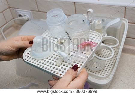 The Process Of Safely Removing Feeding Bottles And Other Items From A Sterilizer Using Tongs. Close-