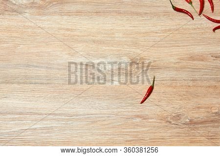 Background - A Lone Pod Of Red Chili Peppers Lies On A Wooden Surface Aside From A Group Of Other Sa