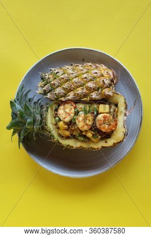 Bird Eye View Pineapple Fried Rice With Shrimps In Pineapple On White Plate With Yellow Backdrop, Ec