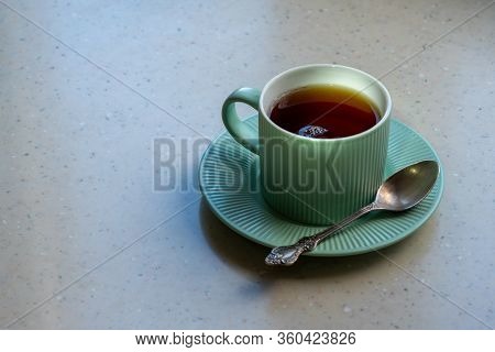 A Pale Green Tea Pair On A Light Artificial Stone Countertop. The Cup Is Filled With Strong Freshly 