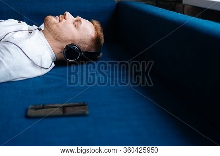 Young Handsome Man Listening To Relaxing Music, Lying On The Couch. Pleasant Music, Relaxation. Conc
