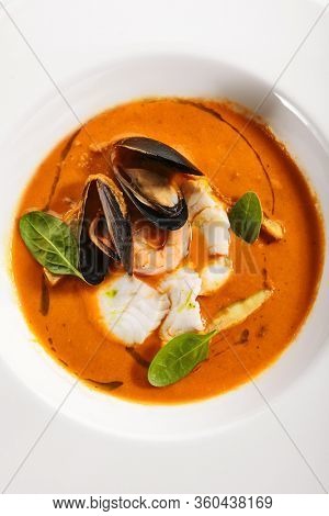 Bouillabaisse in white bowl. Served main course top view. French seafood, soup with fish and mussels. Restaurant food portion, main course. France cuisine. Dinner, gourmet meal in plate