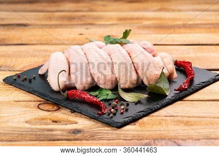 Raw Chicken Wings With Spices On A Black Cooking Board And On A Wooden Background. Fresh Chicken Win