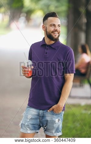 A Young Guy Walking In The Park With Lemonade In The Spring. Spring Day.